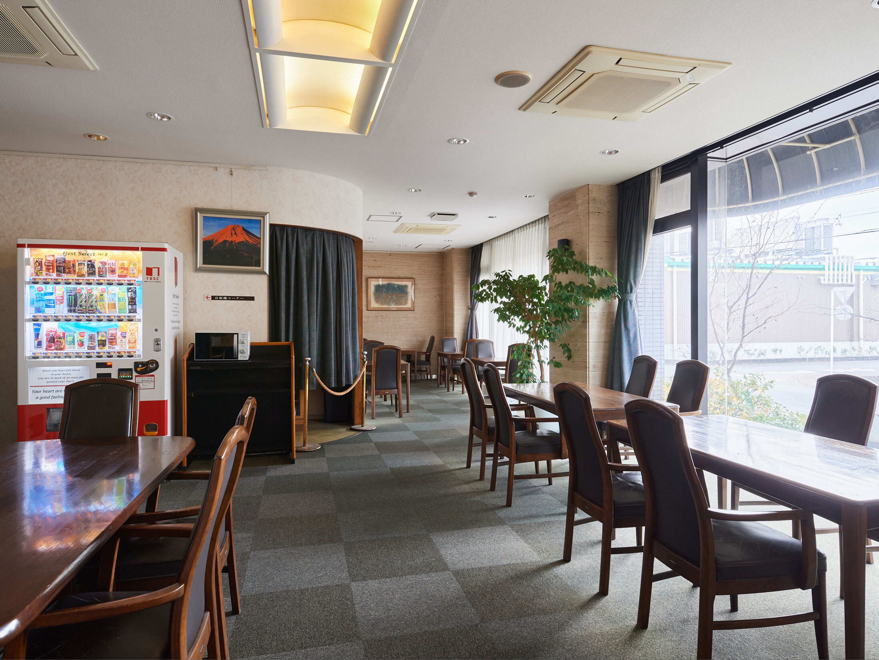 Ein Konferenzraum mit einem langen Tisch, Stühlen, einem Automaten und einem großen Fenster mit Blick nach draußen.