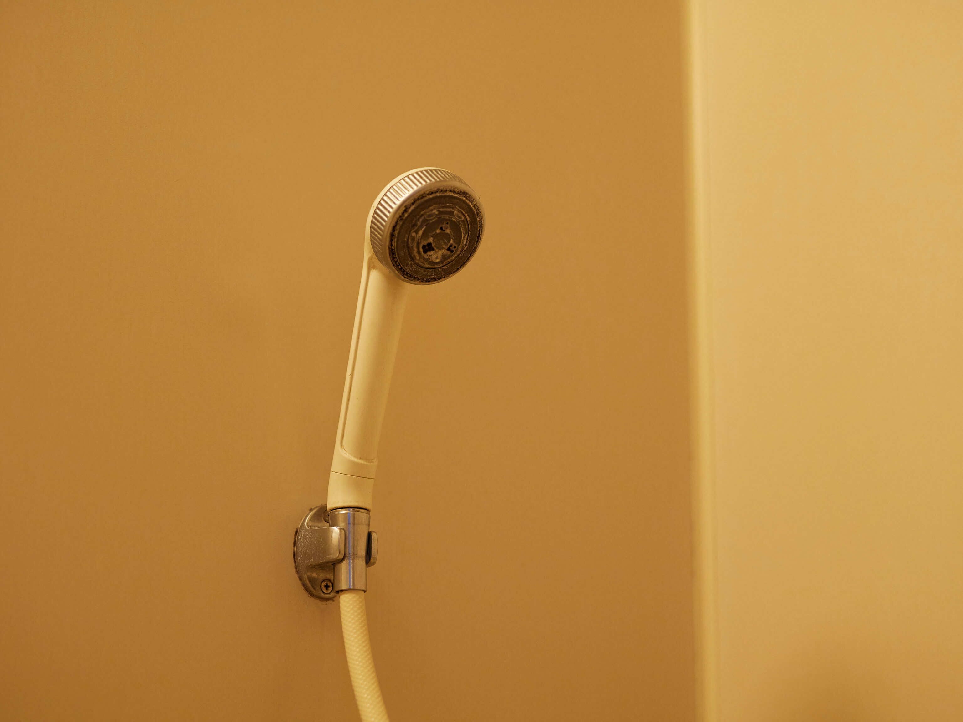 Un cabezal de ducha con una manguera unida a la pared.