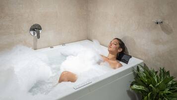 Bathroom features a bathtub and a potted plant.