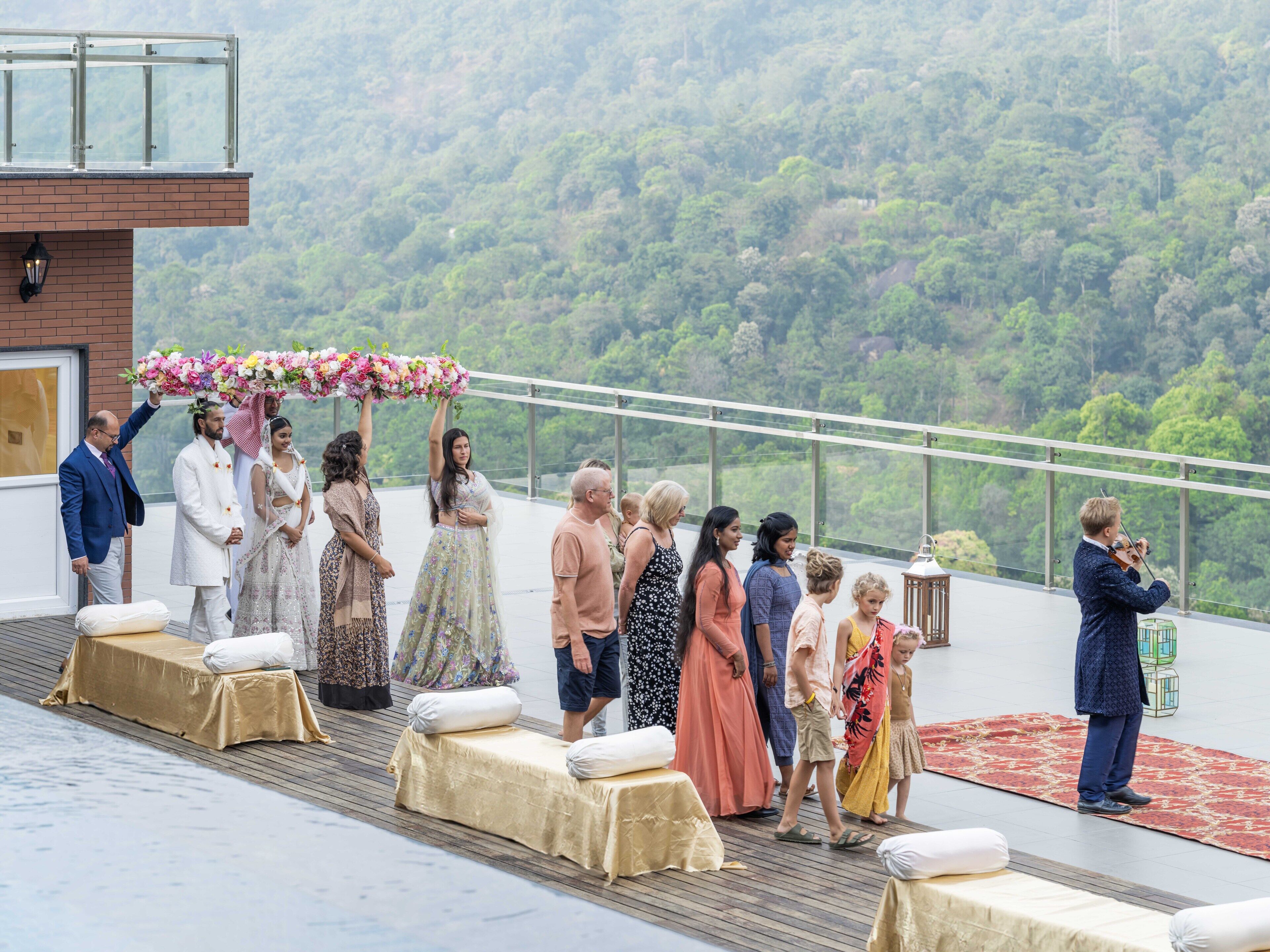 A rooftop event with a scenic forest view, a glass railing, and a covered seating area.