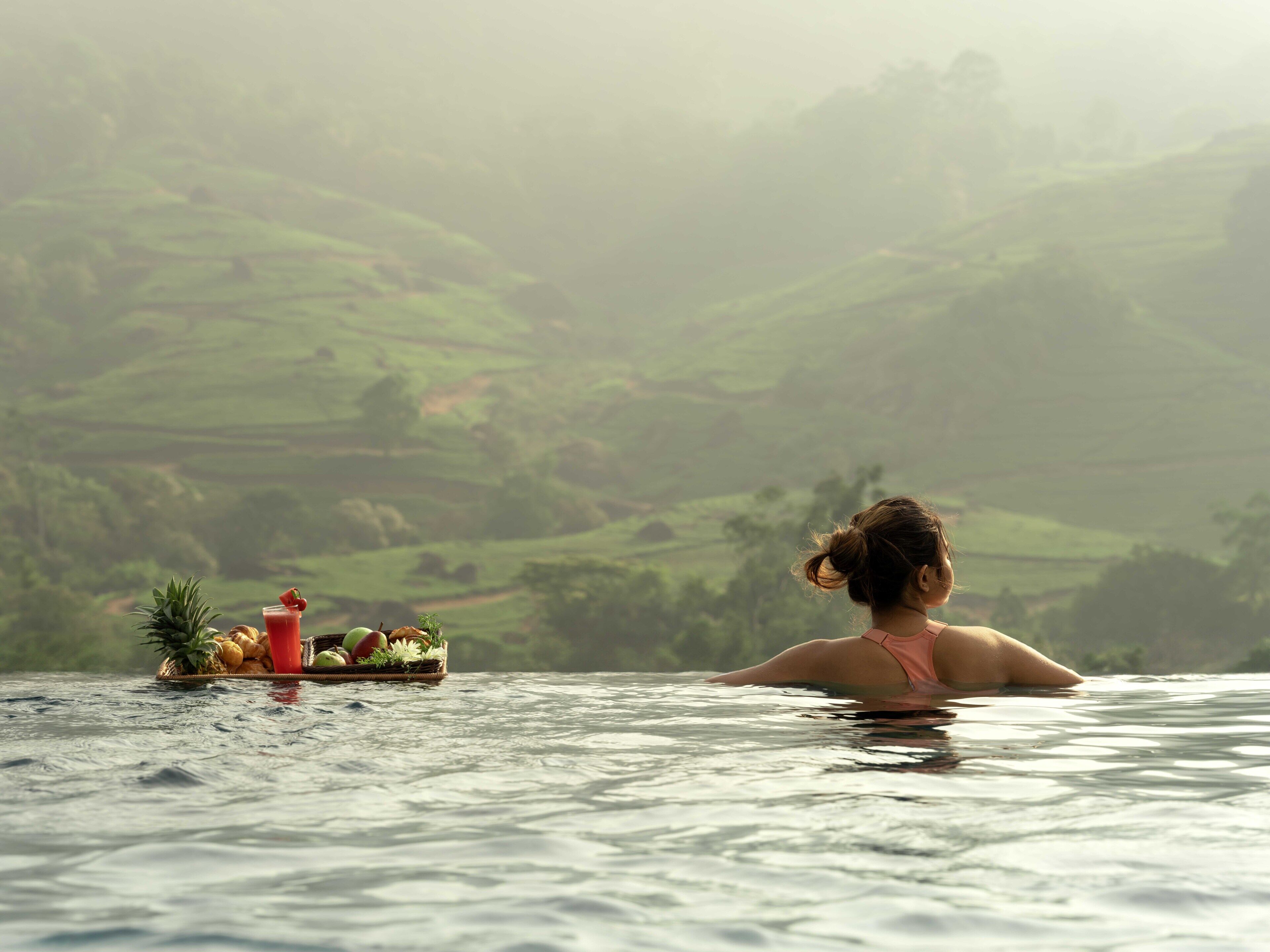 A person in a hot tub overlooking a lush landscape.