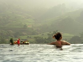 A person in a hot tub overlooking a lush landscape.