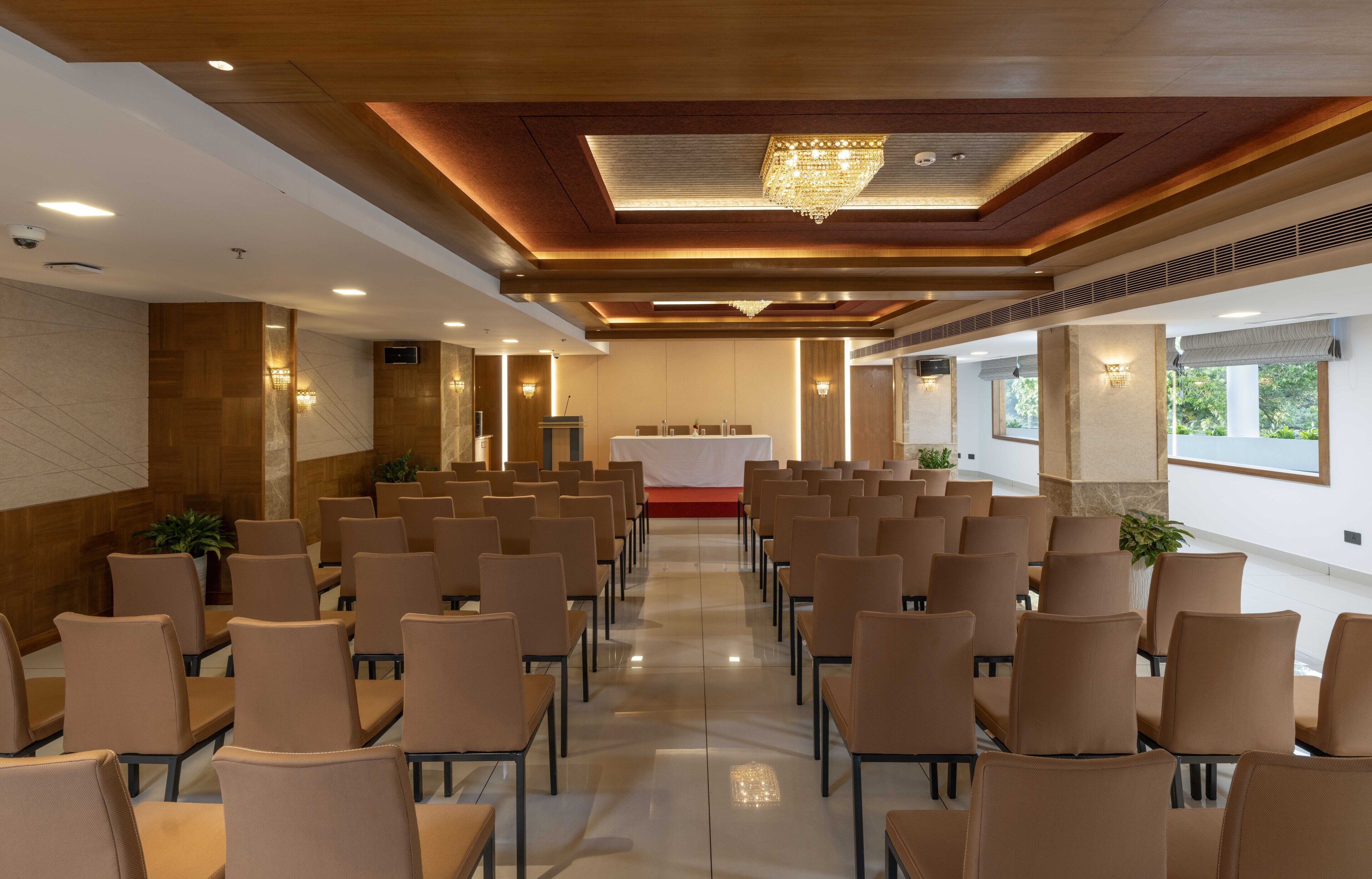 Un salón de conferencias con filas de sillas, un atril y una araña.