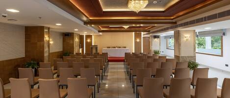 Un salón de conferencias con filas de sillas, un atril y una araña.
