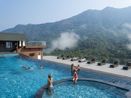 Una piscina al aire libre, sombrillas, sillones reclinables de piscina