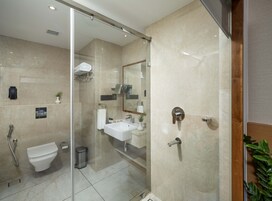 Un baño moderno con cabina de ducha de vidrio, inodoro, lavabo y espejo.