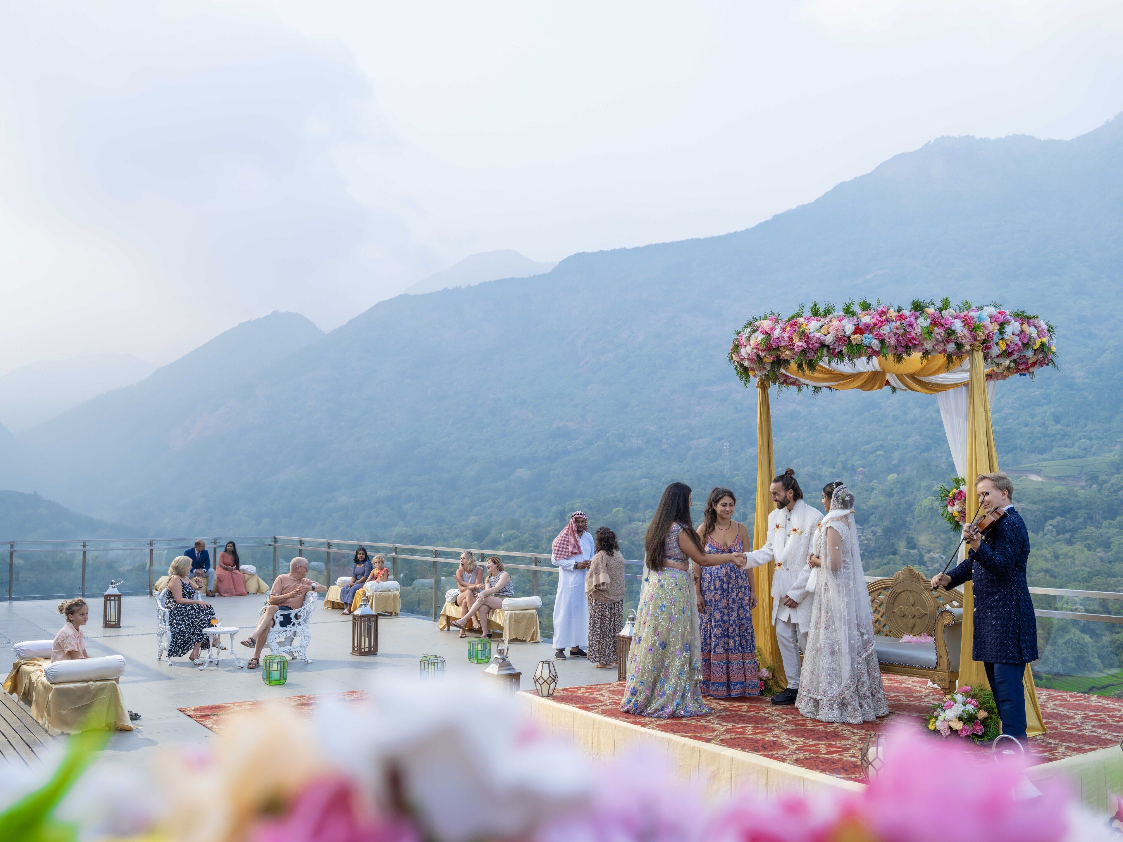 A wedding ceremony on a terrace with a mountainous backdrop.