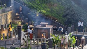 A traditional building with stone carvings, a fire pit, and a group of people gathered around. - The Grand Cliff Resort Munnar  (Devikolam)