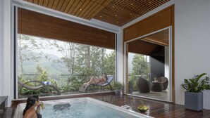 A woman relaxing in a hot tub with a view of a lush landscape. - The Grand Cliff Resort Munnar  (Devikolam)