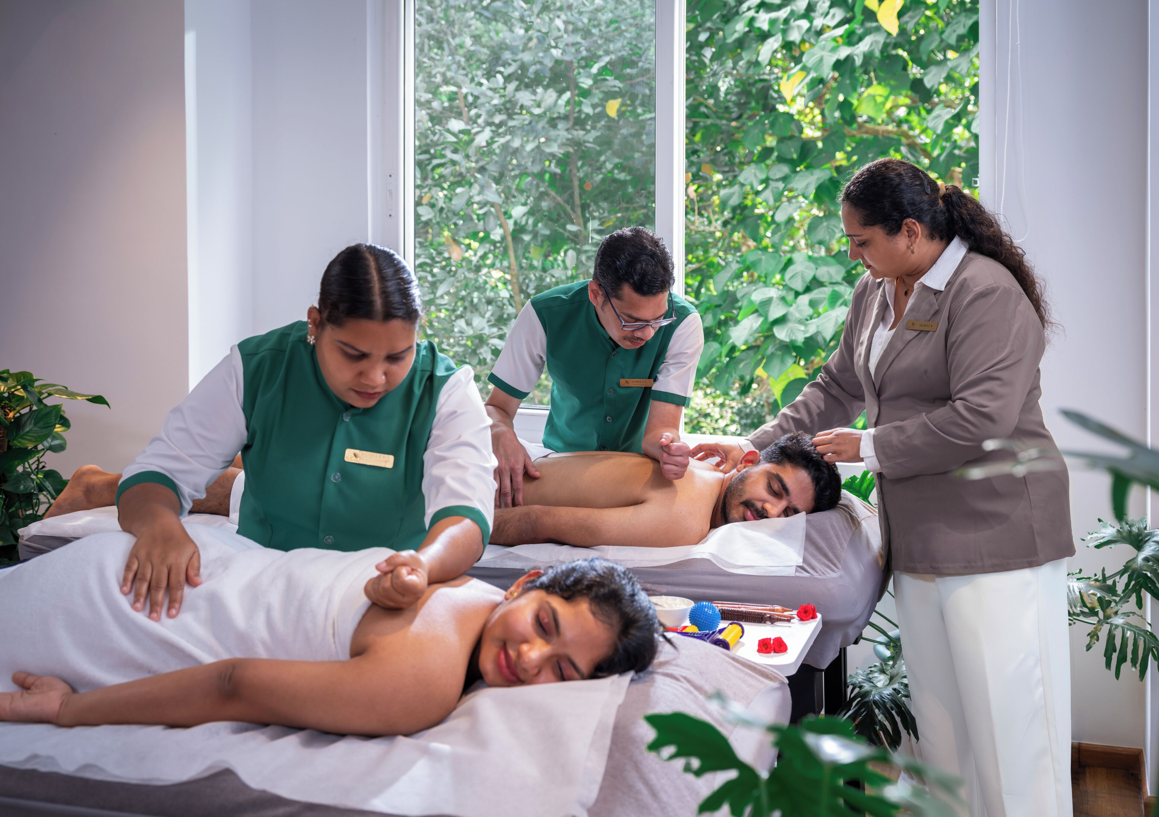 A massage therapy session in a room with large windows, a massage table, and a few plants.