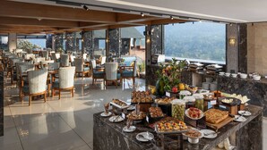 A buffet setup with various food items and a seating area with chairs and tables. - The Grand Cliff Resort Munnar  (Devikolam)