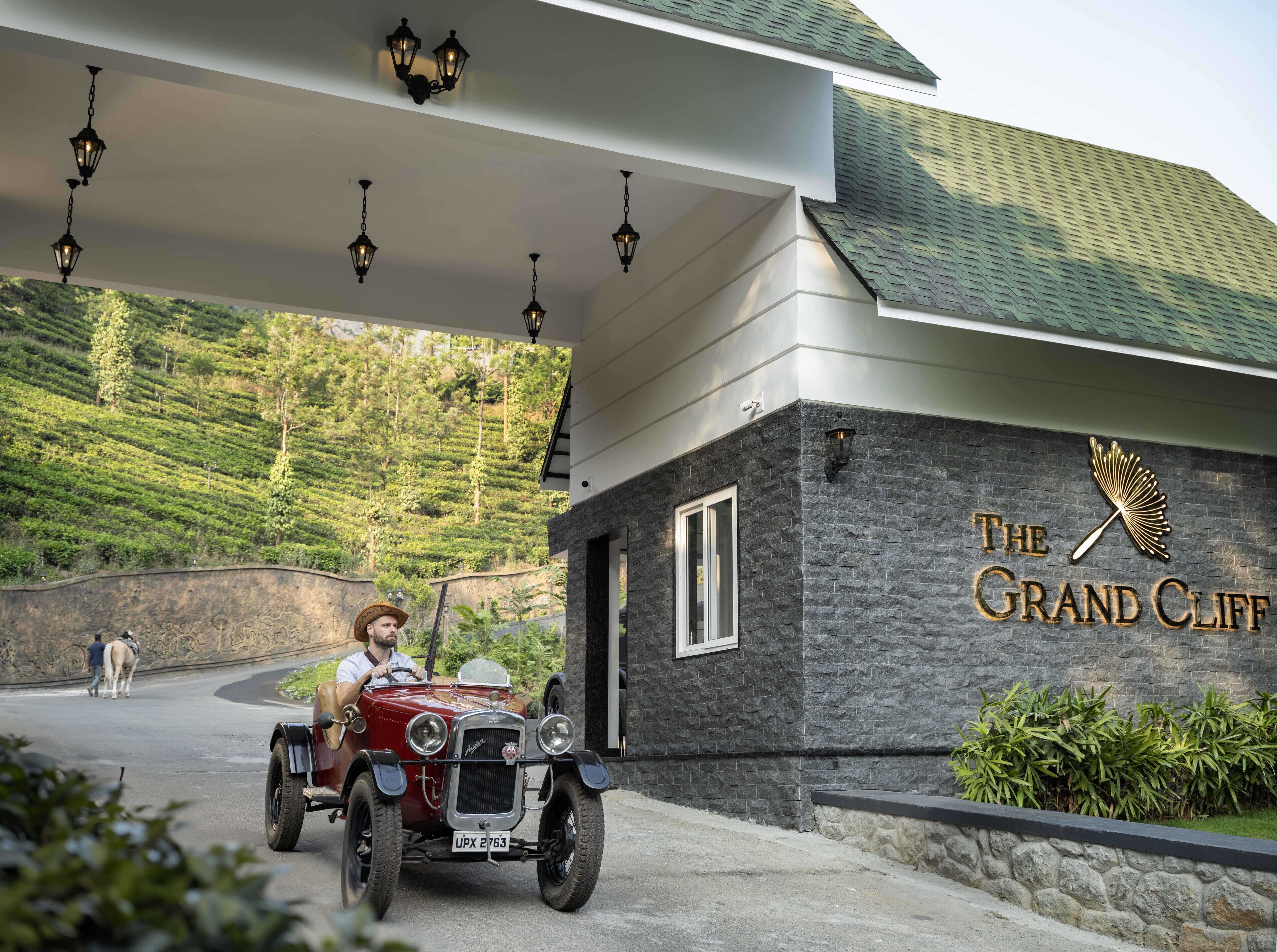 Ein altes Auto parkt vor einem Gebäude, an dem ein Schild mit der Aufschrift "The Grand Cliff" hängt.