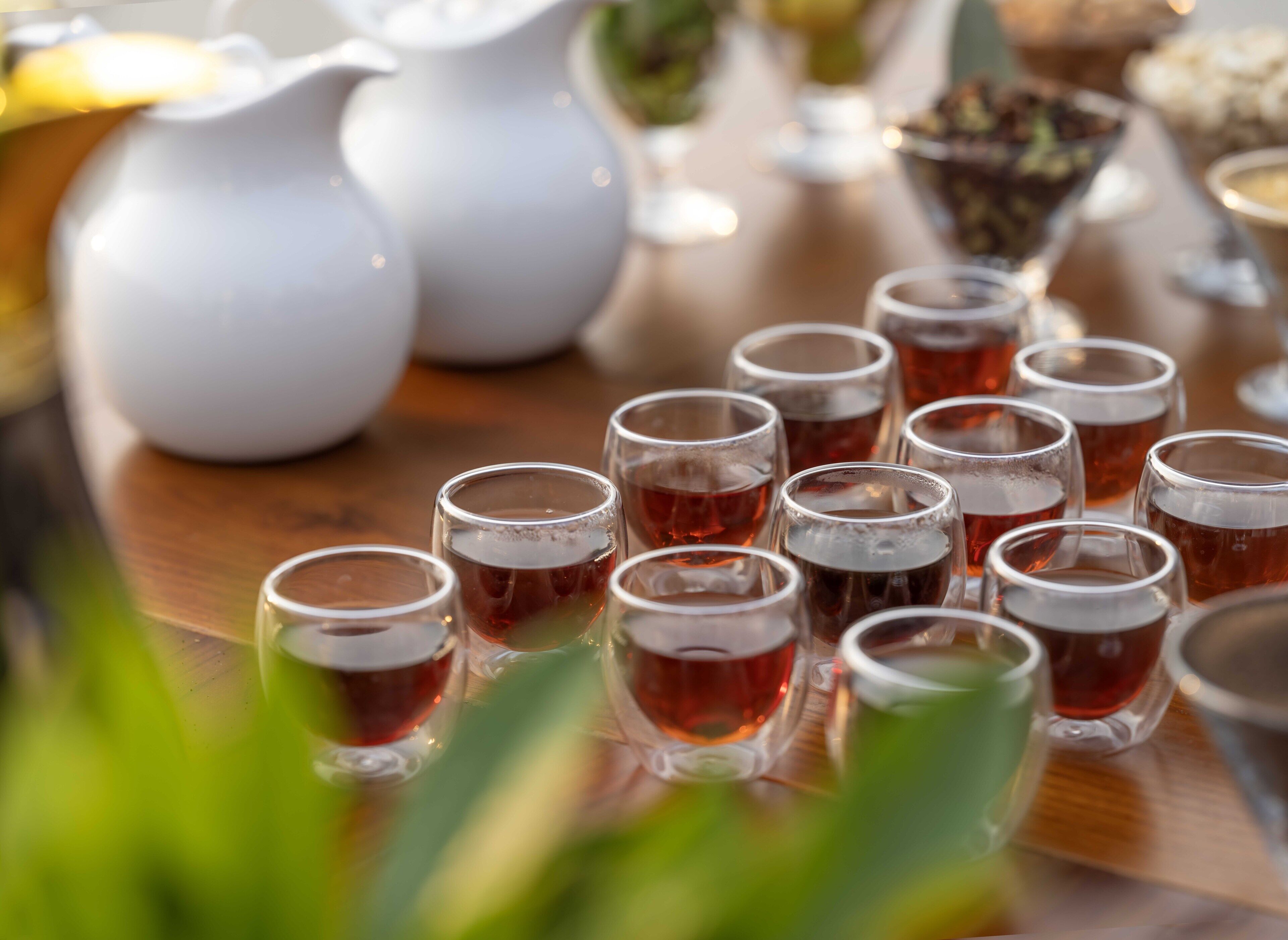 Une table avec plusieurs verres de thé, un pichet blanc et un bol contenant ce qui semble être un aliment.