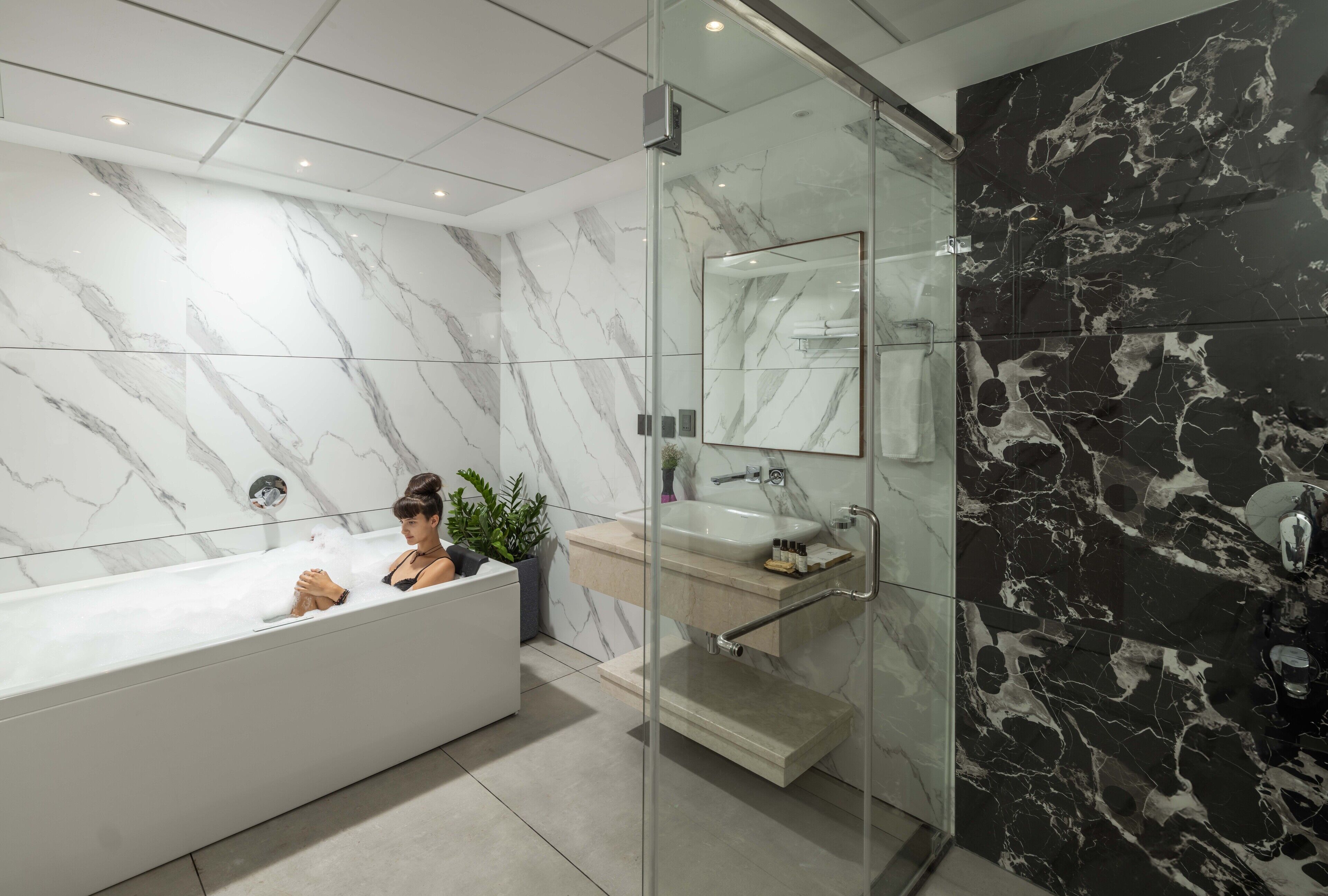 A modern bathroom with a marble vanity, a glass shower enclosure, and a bathtub.