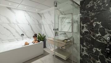 A modern bathroom with a marble vanity, a glass shower enclosure, and a bathtub.
