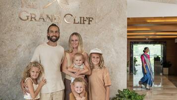 En familie poserer foran en marmorvæg med teksten "The Grand Cliff".