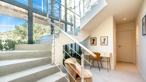 A modern interior with a staircase leading to an upper level, a desk with a chair, and framed artwork on the wall.