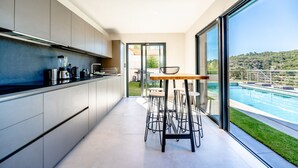 A modern kitchen with a dining area overlooking a pool.