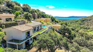 Eine moderne Villa mit Swimmingpool, umgeben von üppiger Vegetation und einem malerischen Meerblick.