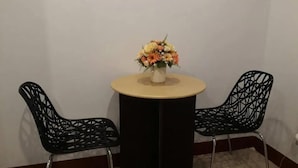 Et lille rundt bord med en blomstervase i midten, placeret mellem to sorte stole med geometrisk mønster.