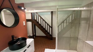 A bathroom with a white sink, a round mirror, a towel rack, and a shower area. - La Maison du Garde (STE OPPORTUNE LA MARE)
