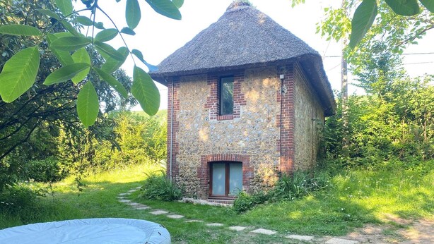 A rustic stone building with a thatched roof, surrounded by greenery. - La Maison du Garde (STE OPPORTUNE LA MARE)