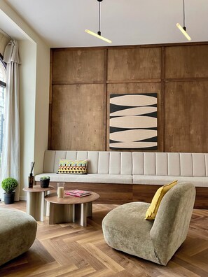 A modern living room with a sofa, round coffee table, and a cushioned armchair. - Hôtel du Théâtre (Bordeaux)