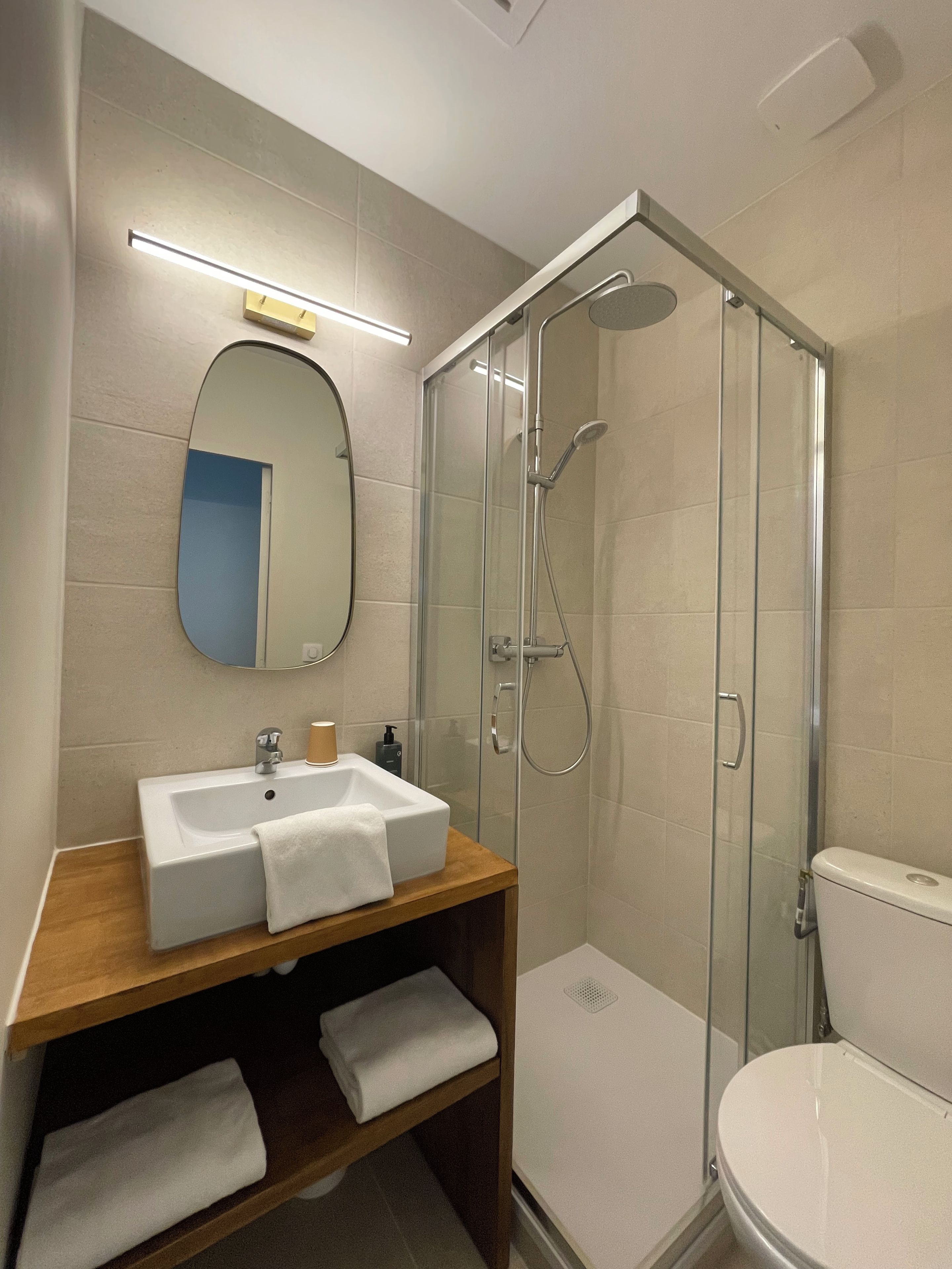 A bathroom with a glass-enclosed shower, a sink with a mirror, and a toilet.