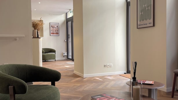 A modern interior with a green armchair, a round coffee table, and a framed artwork on the wall. - Hôtel du Théâtre (Bordeaux)