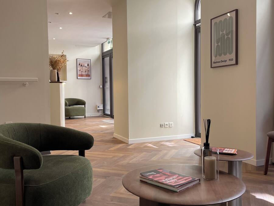 A modern interior with a green armchair, a round coffee table, and a framed artwork on the wall.