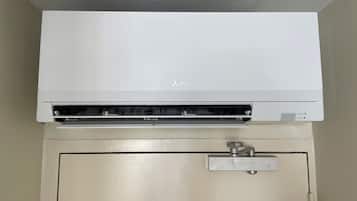 A Mitsubishi air conditioner mounted above a beige door with a control panel below.
