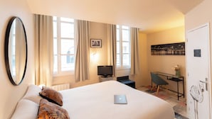 A hotel room with a bed, a desk with a laptop, a television, and a chair. - Hôtel du Théâtre (Bordeaux)