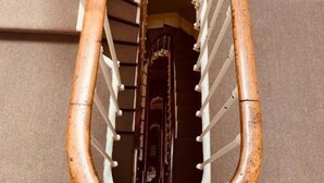 A spiral staircase with a wooden handrail and a metal railing. - Hôtel du Théâtre (Bordeaux)