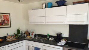 A modern kitchen with white cabinets, a black countertop, a coffee maker, and a dishwasher. - Villa, Plein Coeur du Moulleau-arcachon, 8 Personnes (Arcachon)