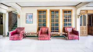 A lobby with three red armchairs, a wooden bench, and a stone staircase. - OYO 2180 Vina Vira Hotel (Lhokseumawe)