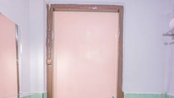 A bathroom with a pink door, a white sink, and green tiled walls.