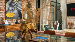 A dining area with a glass table, a book, and a decorative elephant figurine. - Maison Jolie Villa by Betterplace (Canggu)