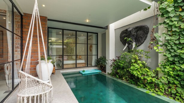 A modern pool area with a hanging chair, a mural of an elephant, and lush greenery. - Maison Jolie Villa by Betterplace (Canggu)