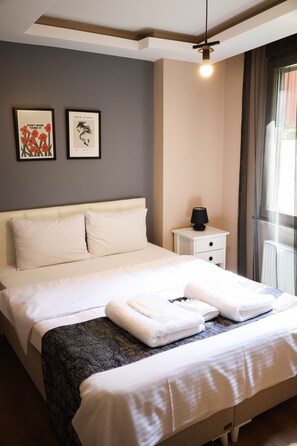 A neatly made bed with white linens, a bedside lamp, and two framed pictures on the wall. - Istanbul Relax Suite (Istanbul)