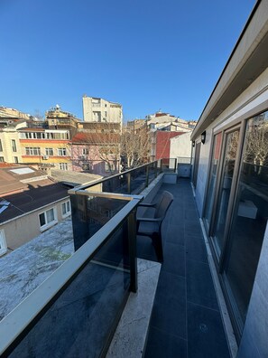 A balcony with a glass railing, a bench, and a view of surrounding buildings. - Istanbul Relax Suite (Istanbul)