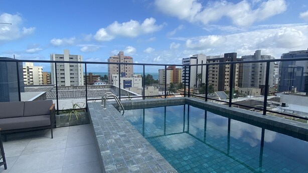 Ein Pool auf dem Dach mit freiem Blick auf die Stadtlandschaft und einer Sitzgelegenheit inklusive Sofa.