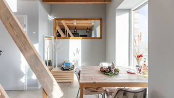 Een eethoek met een houten tafel, stoelen en een spiegel erboven.