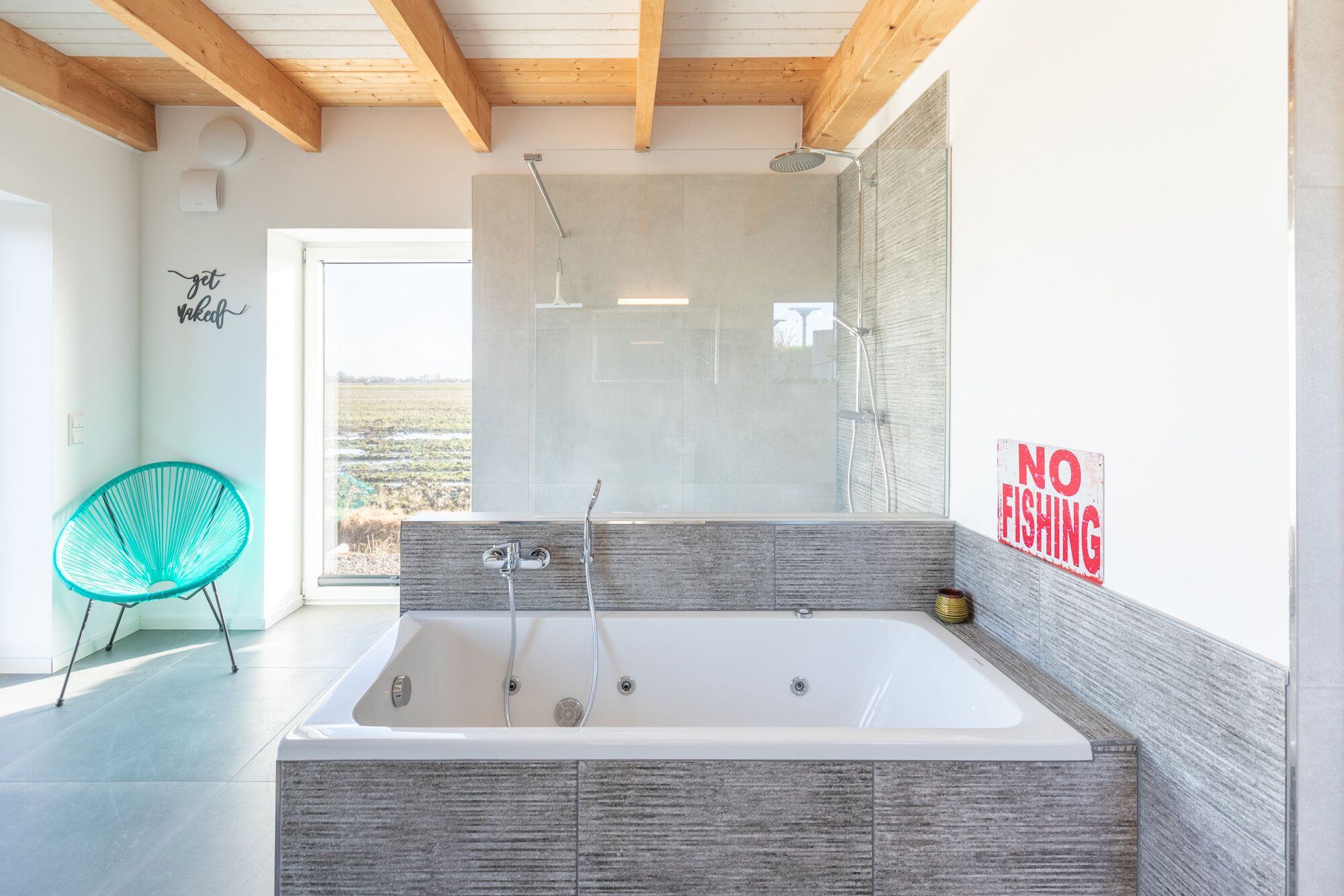 Ein modernes Badezimmer mit einer großen Badewanne, einer Dusche und Blick ins Freie.