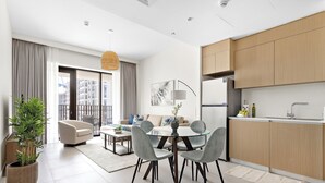 A modern apartment with a dining area, kitchen, and a balcony with a view of buildings. - Silkhaus Surf 1 Dubai Creek Harbour (Dubai)