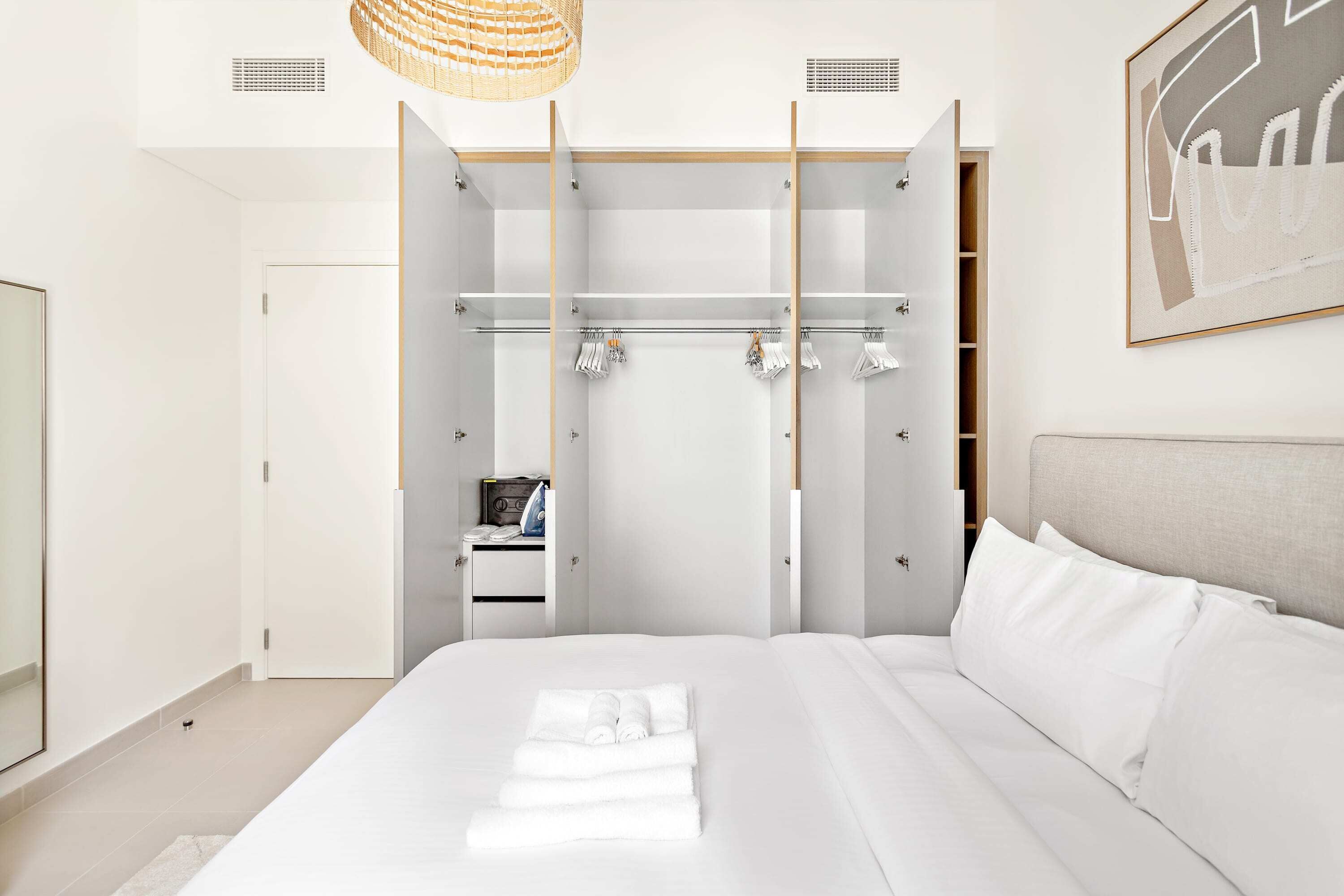 Una habitación de hotel moderna con una cama grande, un armario con espacio para colgar y un televisor de pantalla plana.