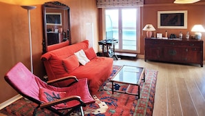 A living room with a sofa, armchair, coffee table, and a patterned rug.