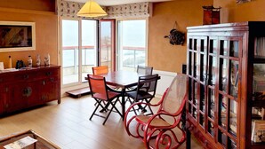 A dining area with a wooden table and chairs, a cabinet with glass doors, and a view through a sliding door.