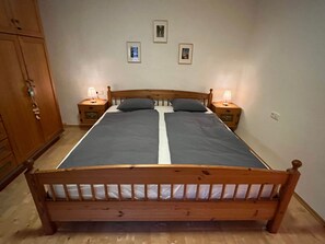 A single bed with a wooden headboard, two bedside tables with lamps, and a wardrobe. - Ferienwohnung Haus am Wald (Marktschellenberg)