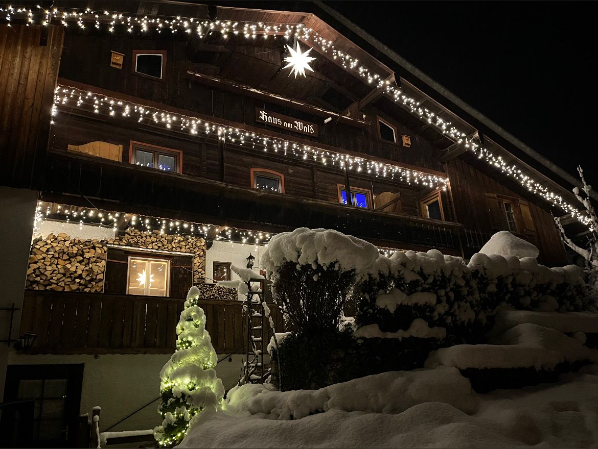 A multi-story wooden building with string lights and a star decoration, surrounded by snow.