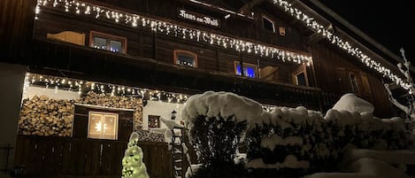 A multi-story wooden building with string lights and a star decoration, surrounded by snow.